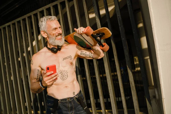 Adult White Shirtless Man Holding Cellphone While Standing Skateboard His — стоковое фото