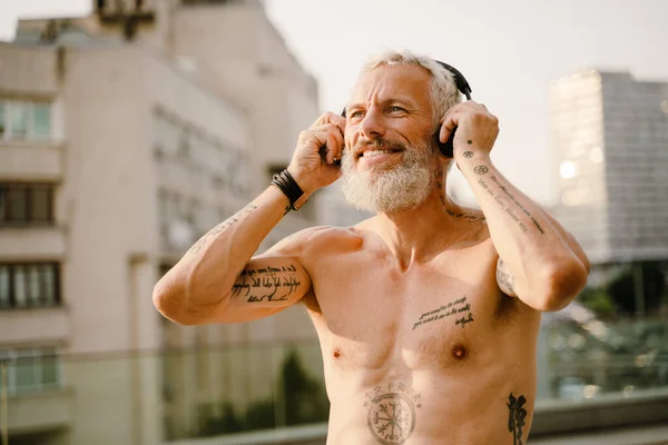 Shirtless Mature Man Listening Music Headphones While Standing Outdoors — Foto Stock