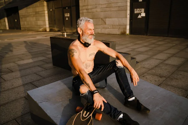 Shirtless Mature Man Wearing Jeans Sitting Skateboard Outdoors — Foto Stock