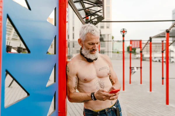 Spor salonunda spor yaparken cep telefonu kullanan beyaz, yetişkin bir adam.