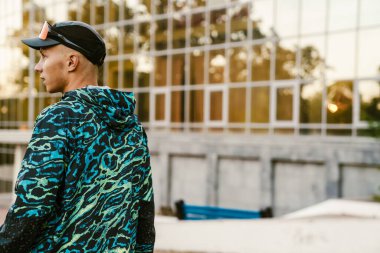 Ceket giyen genç sporcu yaz günü dışarıda çalışıyor.