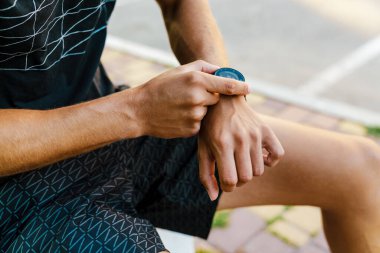 Genç sporcu dışarıda spor yaparken akıllı hareket ediyor.