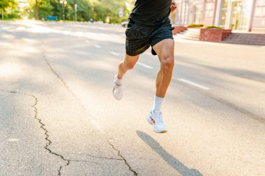 Spor giyim sektöründe genç beyaz bir adam dışarıda antrenman yaparken koşuyor.