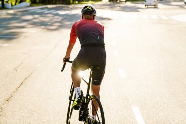 Kasklı genç sporcu dışarıda çalışırken yarış bisikleti sürüyor.