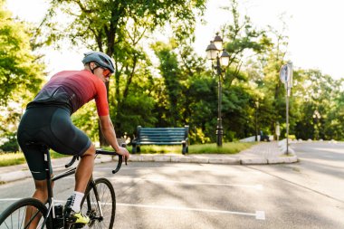 Kasklı genç sporcu dışarıda çalışırken yarış bisikleti sürüyor.
