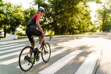 Kasklı genç sporcu dışarıda çalışırken yarış bisikleti sürüyor.