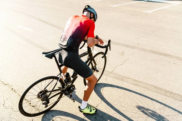 Kasklı genç beyaz bisikletçi şehir yolunda çalışıyor.
