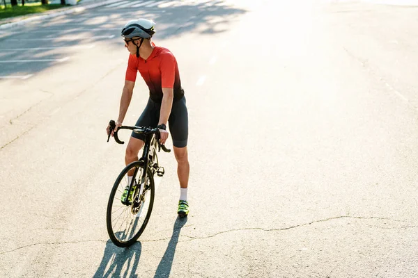 Kasklı genç beyaz bisikletçi şehir yolunda çalışıyor.