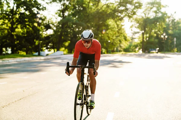 Young sportsman in helmet riding racing bicycle while working out outdoors