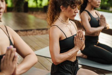 Yoga yaparken meditasyon yapan çok ırklı üç kadın.