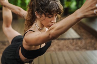 Yoga antrenmanı sırasında dışarıda egzersiz yapan beyaz bir kadın.