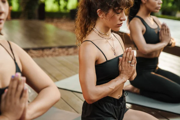 Yoga yaparken meditasyon yapan çok ırklı üç kadın.