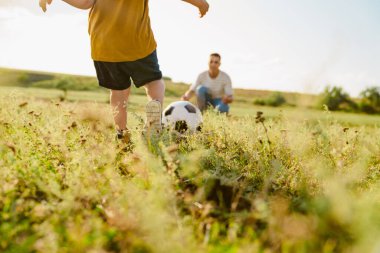 Genç beyaz baba ve küçük oğlu dışarıda futbol oynuyorlar.