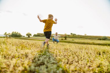 Genç beyaz baba dışarıda oğluyla oynuyor ve onunla dalga geçiyor.