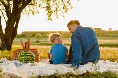 Genç beyaz baba oğluyla yaz sahasında piknik yapıyor.