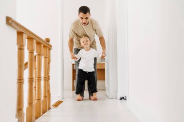 Beyaz adam ve oğlu evde birlikte vakit geçirirken gülüp oynuyorlar.