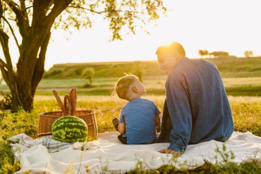 Genç beyaz baba oğluyla yaz sahasında piknik yapıyor.