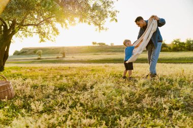 Genç beyaz baba oğluyla yaz tarlasında piknik yapıyor.