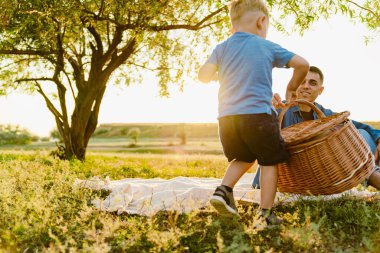 Genç beyaz baba oğluyla yaz tarlasında piknik yapıyor.