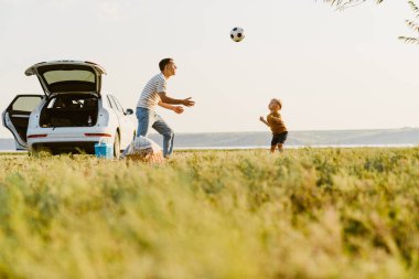 Genç beyaz baba ve oğlu dışarıda futbol oynuyorlar.