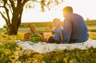 Genç beyaz baba oğluyla yaz sahasında piknik yapıyor.