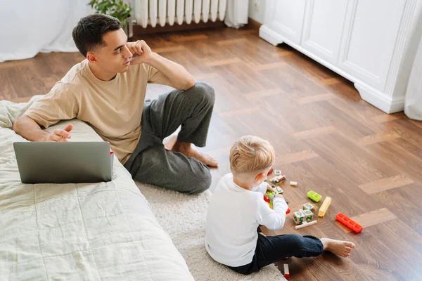 Young Father Talking Cellphone While Spending Time His Son Home — Stockfoto