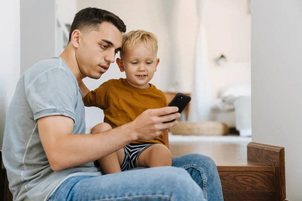 Young Father Son Using Mobile Phone While Sitting Stairs Home — Foto Stock