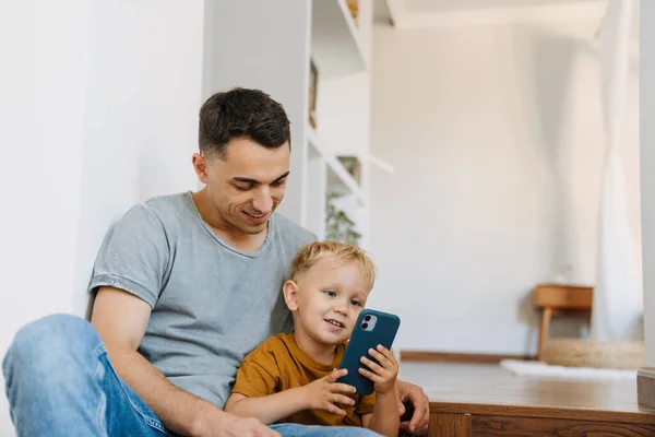Young Father Son Smiling Using Mobile Phone Home — Foto Stock