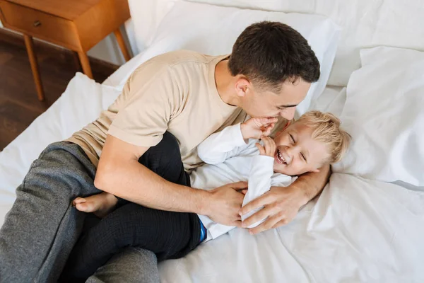 Young White Father Making Fun Playing His Son Bed Home —  Fotos de Stock