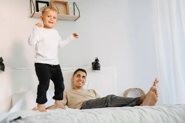 White Boy Laughing Jumping Bed While Spending Time His Father — стоковое фото