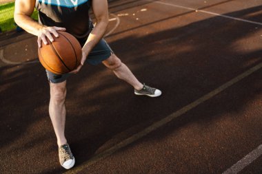 Spor sahasında spor yaparken basketbol oynayan beyaz bir adam.