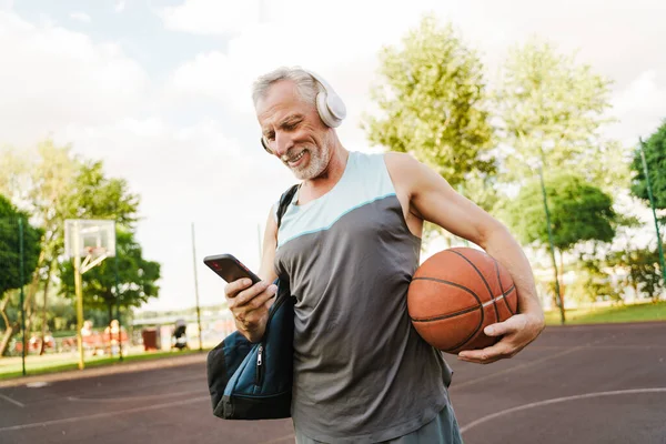 Grey Senior Man Listening Music Using Cellphone Playground — Stock Photo, Image