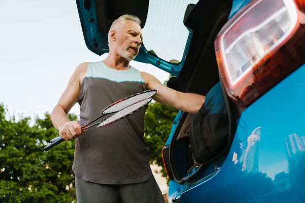 Grey Senior Sportsman Getting Badminton Rackets Out Bag Trunk Outdoors — Zdjęcie stockowe