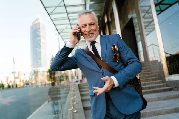 Senior Man Klädd Kostym Talar Mobiltelefon Medan Står Vid Byggnaden — Stockfoto