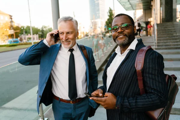 Multiraciala Män Som Använder Mobiltelefoner Stående Genom Att Bygga Utomhus — Stockfoto