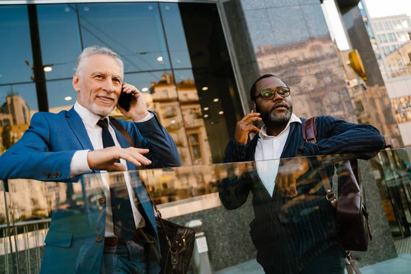 Multiracial Men Talking Cellphones While Standing Building Outdoors — Foto Stock