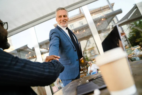 Multiracial Men Smiling Handshaking While Working Laptops Cafe Outdoors — Photo