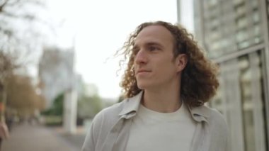 Güzel kıvırcık saçlı adam dışarıda yürüyor.