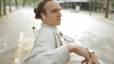 Dışarıda kulaklıkla müzik dinleyen kıvırcık saçlı yakışıklı bir adam.