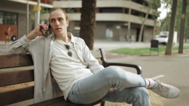 Açık havada telefonla konuşan mutlu kıvırcık saçlı adam.