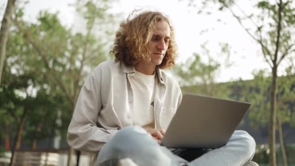 Positive Curly Haired Man Working Laptop While Sitting Outdoors — Vídeo de stock