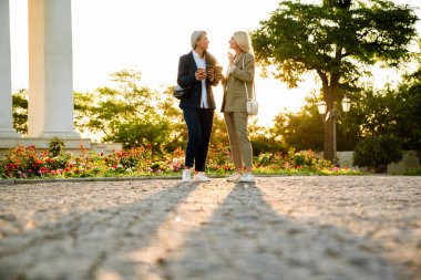 Olgun çok ırklı iş kadınları açık havada buluşup kahve içiyorlar.