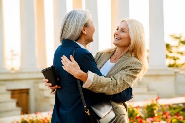 Olgun, çok kültürlü iş kadınları dışarıda toplanırken gülüp sarılıyorlar.
