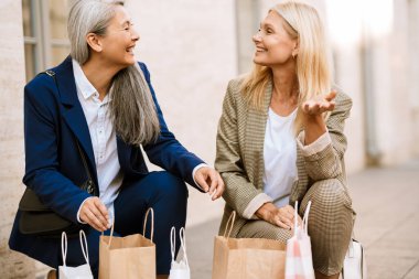 Dışarıda alışveriş yaparken gülümseyen çok kültürlü kadınlar.