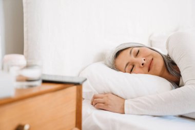 Gri Asyalı kadın evde yatarken uyuyor.