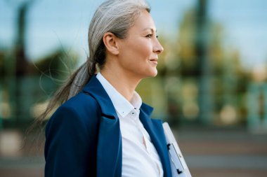 Takım elbiseli gri Asyalı kadın dışarı bakıyor.