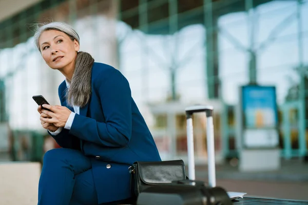 Grå Asiatisk Kvinna Använder Mobiltelefon Medan Sitter Bänken Vid Flygplatsen — Stockfoto
