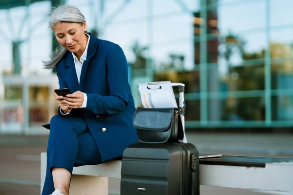 Сіра Азіатська Жінка Використовуючи Мобільний Телефон Сидячи Лавці Аеропорту Відкритому — стокове фото