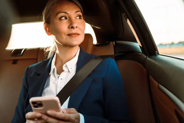 Olgun Asyalı Kadını Araba Kullanırken Cep Telefonu Kullanıyor — Stok fotoğraf