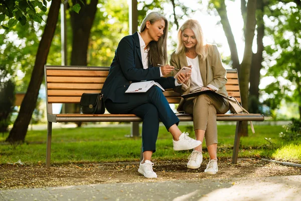 Mature Multiracial Businesswomen Using Cellphone While Working Park Outdoors — Zdjęcie stockowe